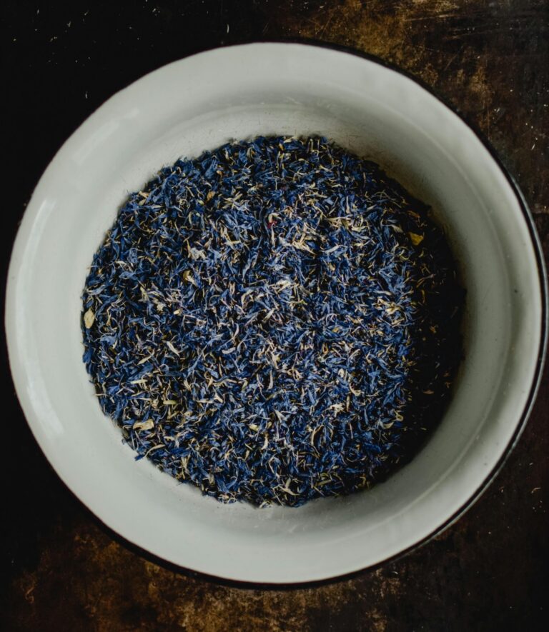 Dried cornflower petals sit in a white bowl